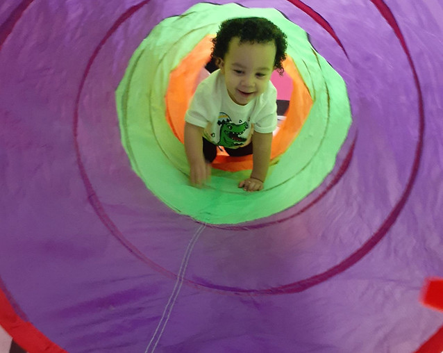 A Tippy Toes student playing in a colorful tunnel